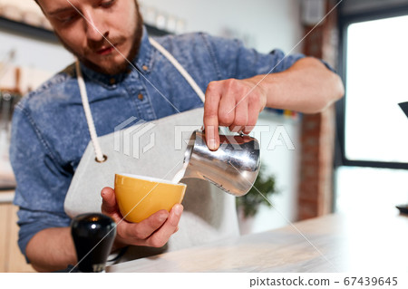 Young barista makes latte in coffee shop 67439645