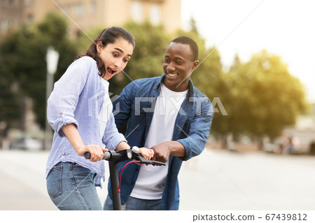 Guy and girl having ride on electric kick scooter 67439812