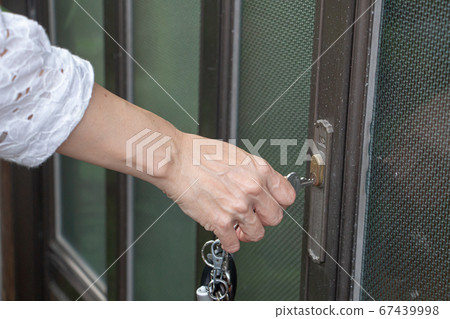 A woman who locks the door of the entrance A woman who locks the door of the entrance 67439998