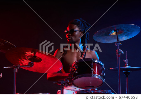 expressive artictic black man playing drums isolated over neon background 67440658