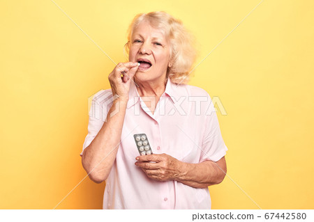 old beautiful blonde woman takes a pill. 67442580