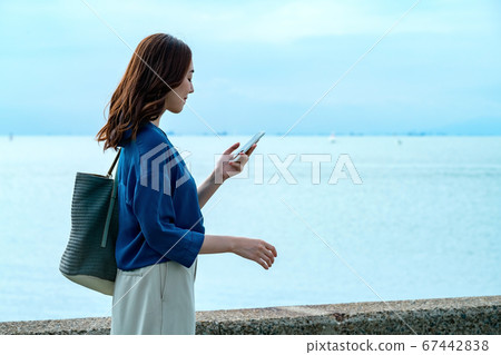 A young woman in the sea operating a smartphone A young woman in the sea operating a smartphone 67442838