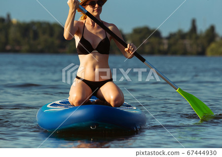 Young attractive woman sitting on paddle board, SUP. Active life, sport, leisure activity concept 67444930