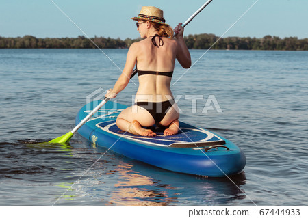 Young attractive woman sitting on paddle board, SUP. Active life, sport, leisure activity concept 67444933