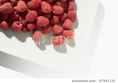 Fresh raspberries on square caremic plate. Close up photo of sweet forest berries with bright sunlight. 67447132