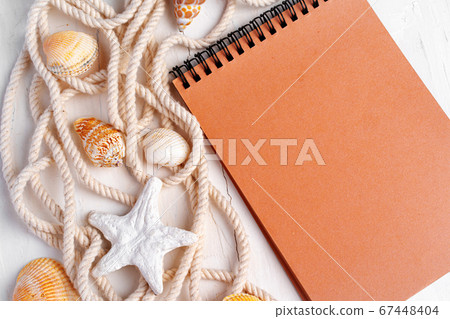 Close up photo of brown notepad with sea shells on wooden planks closeup Close up photo of brown notepad with sea shells on wooden planks closeup 67448404