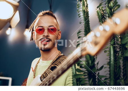 Young fashionable man in pink sunglasses playing guitar with joy 67448696