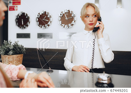 Female receptionist in hotel talking on the phone at work Female receptionist in hotel talking on the phone at work 67449201