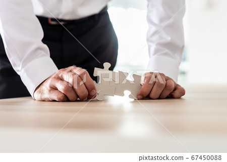 Businessman connecting two matching puzzle pieces 67450088