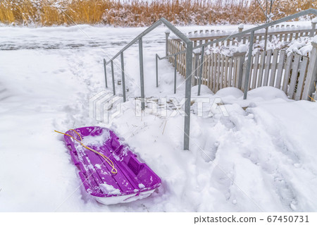 Purple sled beside an outdoor stairs in winter 67450731