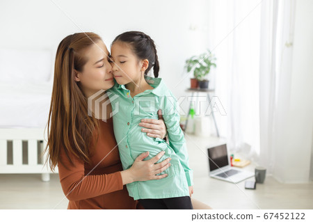 Asian mother and daughter embrace and happily kiss their cheeks with love. family concept. 67452122