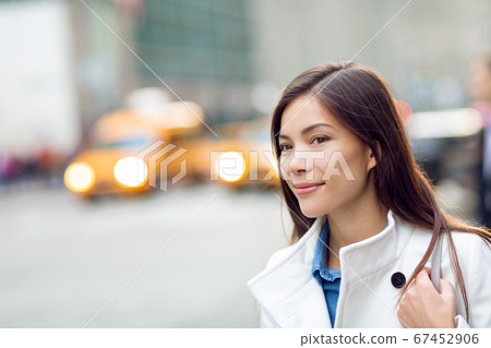 New Yorker woman walking on New York City street waiting for car lift rideshare taxi. Asian young professional with yellow taxi cabs cars traffic in background. Biracial person New Yorker woman walking on New York City street waiting for car lift rideshare taxi. Asian young professional with yellow taxi cabs cars traffic in background. Biracial person 67452906