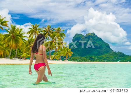 Travel paradise beach woman walking in water beach on holidays vacation Tahiti Travel paradise beach woman walking in water beach on holidays vacation Tahiti 67453780