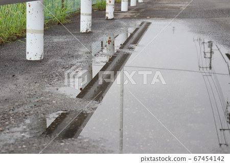 Guardrail reflected in a puddle Guardrail reflected in a puddle 67454142