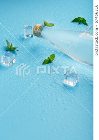A bottle of ice water, ice cubes, drops and mint A bottle of ice water, ice cubes, drops and mint 67456816