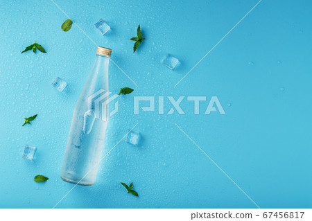A bottle of ice water, ice cubes, drops and mint A bottle of ice water, ice cubes, drops and mint 67456817