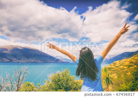 New Zealand travel wanderlust happy tourist woman with v sign hand up at Wanaka lake landscape summer destination. Adventure young girl excited traveling the world alone 67456917