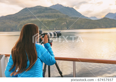 Travel photographer with professional telephoto lens camera on tripod shooting wildlife in Alaska, USA. Scenic cruising inside passage cruise tourist vacation adventure. Woman taking photo picture Travel photographer with professional telephoto lens camera on tripod shooting wildlife in Alaska, USA. Scenic cruising inside passage cruise tourist vacation adventure. Woman taking photo picture 67457937