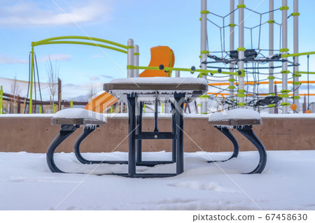 Frosty table and bench against playground and sky Frosty table and bench against playground and sky 67458630