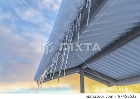 Frosted roof with icicles against cloudy sky Frosted roof with icicles against cloudy sky 67458632