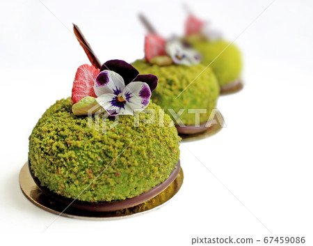 Green textured pistachio desserts with edible flowers and strawberries 67459086