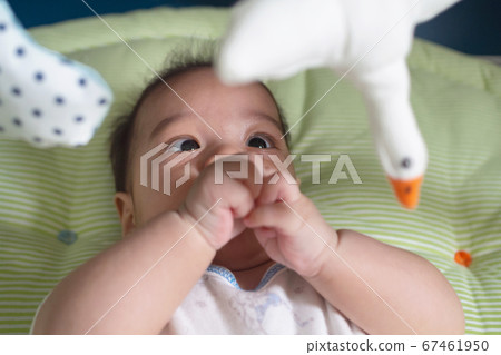 asian innocent baby newborn boy looking and play mobile hanging toy on fabric crib. asian innocent baby newborn boy looking and play mobile hanging toy on fabric crib. 67461950