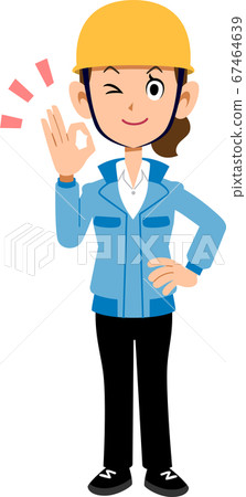 Woman in blue work clothes wearing a helmet giving an OK sign 67464639