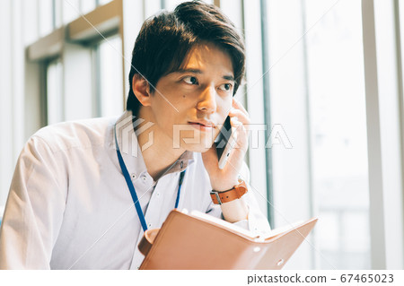 一個年輕人用筆記本打電話 67465023