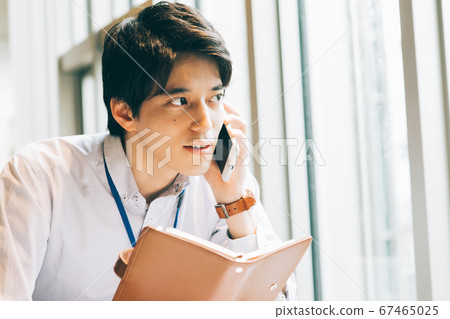 一個年輕人用筆記本打電話 一個年輕人用筆記本打電話 67465025