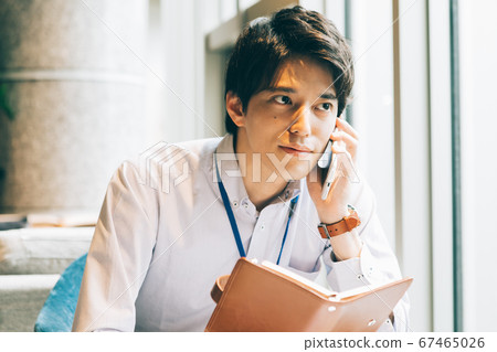 一個年輕人用筆記本打電話 一個年輕人用筆記本打電話 67465026