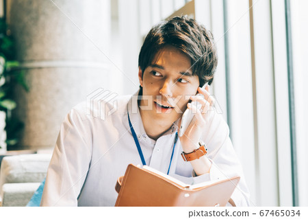 A young man calling with a notebook A young man calling with a notebook 67465034