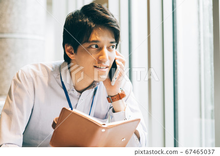 一個年輕人用筆記本打電話 一個年輕人用筆記本打電話 67465037