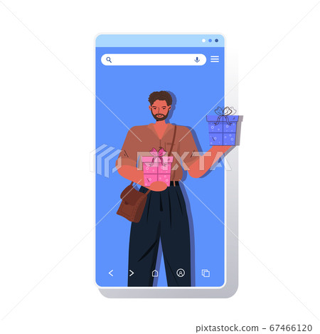 man celebrating online birthday party guy in smartphone screen holding gift boxes man celebrating online birthday party guy in smartphone screen holding gift boxes 67466120