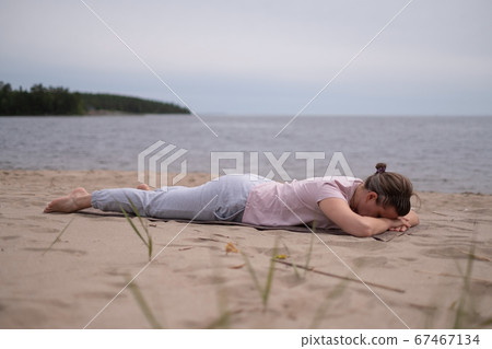 Sporty woman relaxing in yoga asana Makarasana or crocodile pose Sporty woman relaxing in yoga asana Makarasana or crocodile pose 67467134