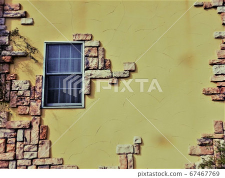 Brick built yellow wall and blue window 67467769