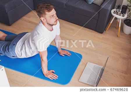 Young man doing yoga in his living room Young man doing yoga in his living room 67469628