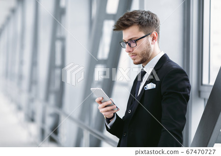 Serious urban business man texting on cell phone in airport 67470727