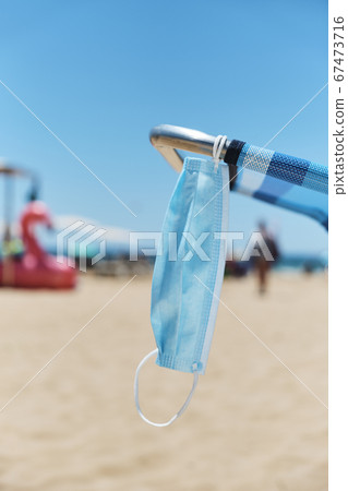 surgical mask hanging on a deck chair on the beach surgical mask hanging on a deck chair on the beach 67473716