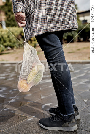 man carrying a mesh bag full of fruit and vegs 67473722