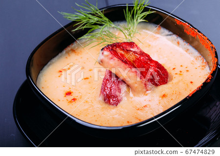 Cream soup with pieces of fish or salmon fillet in a black dishes on a wooden table 67474829