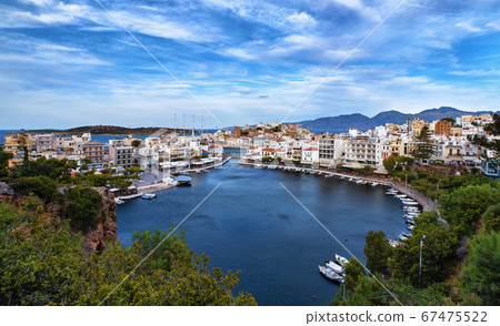 Colorful view of Voulismeni lake and Agios Nikolaos town on Crete island, Greece in evening with beautiful clouds on blue sky. 67475522