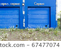 overgrown entry into the gates of an abandoned car service. it is written on the facade - quick service and service 67477074