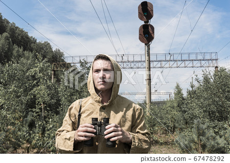 a man with binoculars in his hands looks into the distance. abandoned old railway a man with binoculars in his hands looks into the distance. abandoned old railway 67478292