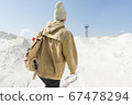 a man with a backpack walks along the white sand towards an abandoned old iron tower 67478294