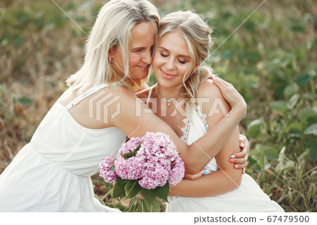 Mother with beautiful daughter in a autumn field Mother with beautiful daughter in a autumn field 67479500