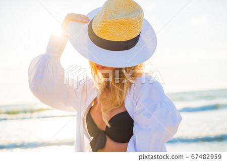 Content woman in bikini and hat on beach Content woman in bikini and hat on beach 67482959