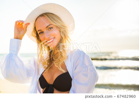 Content woman in bikini and hat on beach Content woman in bikini and hat on beach 67482960