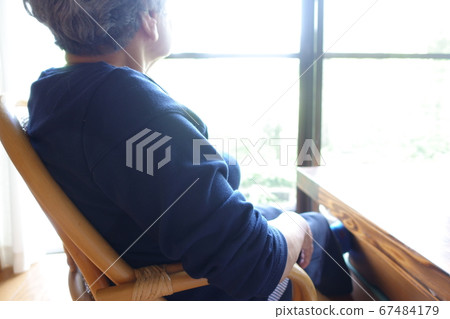 Grandma senior woman sitting by the window and looking out 67484179