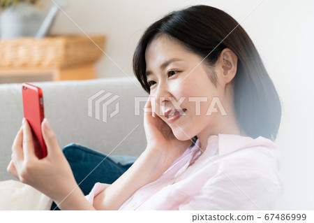 A middle woman looking at a smartphone in the living room A middle woman looking at a smartphone in the living room 67486999