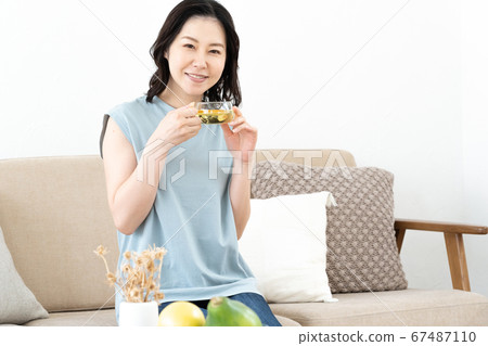 Middle woman drinking herbal tea on sofa Middle woman drinking herbal tea on sofa 67487110
